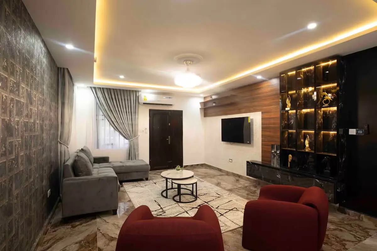 Living room with grey sofa, red armchairs and feature lighting