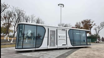 Capsule home with wide tinted windows on a paved site
